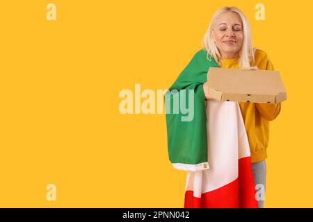 Femme mature avec drapeau de l'Italie et pizza sur fond jaune Banque D'Images