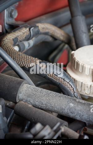 vue rapprochée de la couche extérieure en caoutchouc fissurée et décollée du flexible hydraulique automobile, du flexible défectueux détérioré cassé avec fil tissé visible Banque D'Images