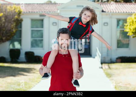Père et fils marchant dans le parc scolaire. Un père qui donne son pigeyback après son retour de l'école. Banque D'Images