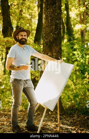 Tirer de la vie. Forêt peintre. Concept d'art. Peinture dans la nature. Démarrer une nouvelle photo. Peintre avec chevalet et toile. Capturez l'instant. Barbu Banque D'Images