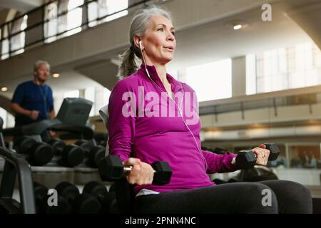 Vérifiez votre respiration lorsque vous soulevez des poids. Portrait d'une femme âgée travaillant avec des poids à la salle de gym. Banque D'Images