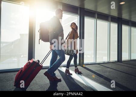 Je ne laisse pas aller de votre main pendant une seconde. un jeune couple marchant ensemble dans un aéroport avec ses bagages tout en tenant les mains. Banque D'Images