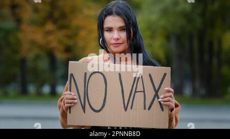 Jeune femme hispanique confiante tenant un carton signe no vax protestant contre la vaccination en plein air sérieuse fille debout dans la rue démontre Banque D'Images