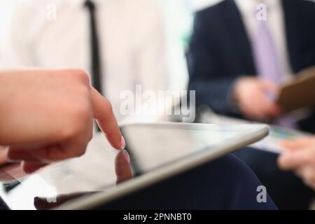Une femme tient la tablette entre les mains et explique les informations à son collègue Banque D'Images