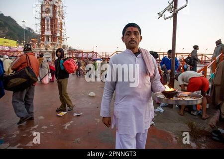 Pandit local avec une lampe à la main, énonciation des mantras pendant le coucher du soleil sur les marches de Haridwar Banque D'Images