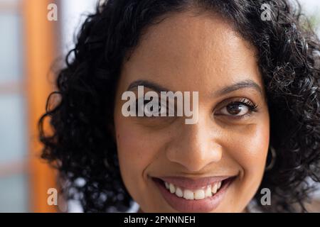 Portrait d'une femme biraciale heureuse médecin regardant l'appareil photo et souriant Banque D'Images