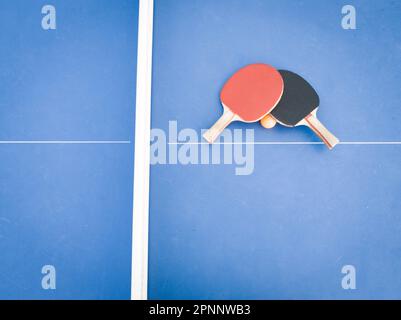 Deux raquettes de ping-pong professionnelles reposant sur une table de ping-pong bleu vif, préparées pour un match de compétition Banque D'Images