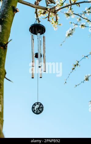 Carillon de vent avec symbolisme zen accroché à l'arbre en fleur avec fond de ciel Banque D'Images