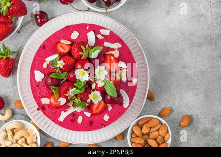 Dessert végétalien. Gâteau aux fruits frais à la noix de cajou avec fraises fraîches, cerises et noix dans une assiette. Vue de dessus. Alimentation saine Banque D'Images