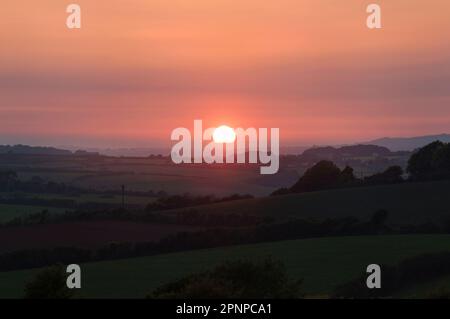 Coucher de soleil sur la campagne de la péninsule de Lizard dans les Cornouailles. Le soleil rouge chaud se couche sur la campagne anglaise lors d'une journée d'été Banque D'Images