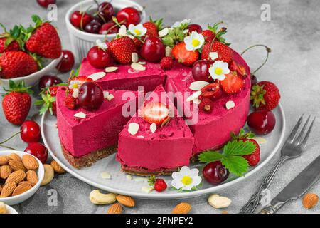 Dessert végétalien. Émincé de cake de cajou aux baies crues avec des fraises fraîches et des cerises dans une assiette. Alimentation saine Banque D'Images