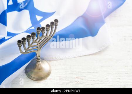 Bonne Hanoukkah. Hanoukkah vieille Menorah sur fond de drapeau israélien avec lumière du soleil ou bokeh sur fond de bois blanc. Image religieuse de jewis Banque D'Images