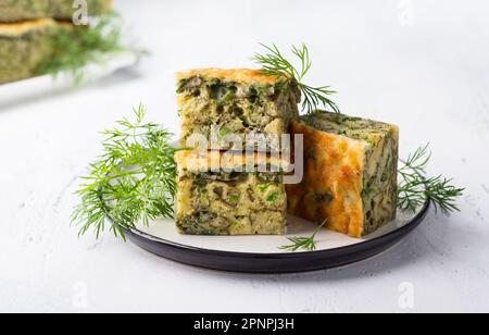 Délicieuse tarte maison aux épinards, au sorrel, aux oignons verts et au fromage décoré d'aneth sur un fond bleu clair Banque D'Images