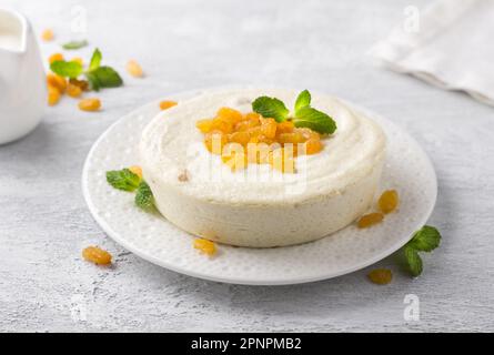 Délicate cocotte de fromage cottage à vapeur avec raisins secs et menthe sur fond gris clair. Délicieux plats végétariens faits maison Banque D'Images