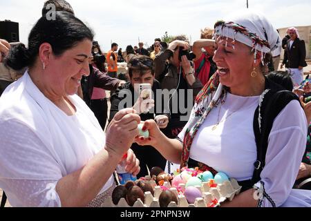 Deux femmes Yazidi sont vues en échangeant joyeusement des oeufs peints lors de la célébration du mercredi rouge des vacances dans le village de Bacinê. Les Kurdes Yazidi vivant dans le village de Bacine du district de Midyat et des districts de Besiri en Turquie ont célébré la fête du mercredi rouge, connue sous le nom de 'Charshema SOR' en kurde, joyeusement avec divers divertissements. Des hommes, des femmes et des enfants de 10 familles yazidi vivant dans le village de Bacine se sont réunis au Centre culturel Yazidi après les prières du matin, portant les robes les plus colorées et les plus belles. Yazidis croient que avril est un mois de printemps Saint et que le monde était créat Banque D'Images