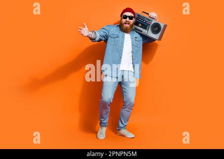 Photo pleine longueur d'un DJ enthousiaste, jeune, qui réunit des amis pour la fête du rock, tenir la boîte de perche isolée sur fond de couleur éclatante Banque D'Images