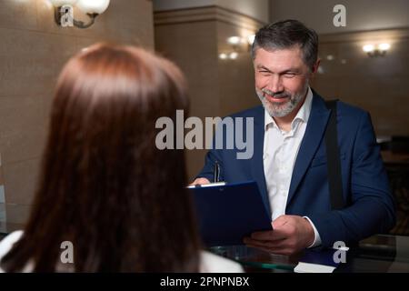 Le client est venu à l'hôtel et signe le document Banque D'Images
