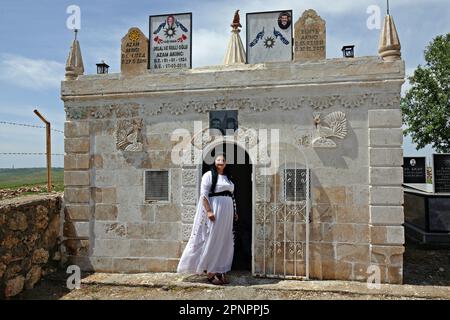 Une femme yazidi assistant à la célébration du Red Wednesday Eid dans le village de Bacinê visite le mausolée de son père. Les Kurdes Yazidi vivant dans le village de Bacine du district de Midyat et des districts de Besiri en Turquie ont célébré la fête du mercredi rouge, connue sous le nom de 'Charshema SOR' en kurde, joyeusement avec divers divertissements. Des hommes, des femmes et des enfants de 10 familles yazidi vivant dans le village de Bacine se sont réunis au Centre culturel Yazidi après les prières du matin, portant les robes les plus colorées et les plus belles. Yazidis croient que avril est un mois de printemps Saint et que le monde a été créé en cela Banque D'Images