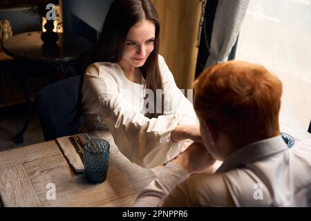 Le jeune homme aux cheveux rouges embrasse la main de son compagnon Banque D'Images