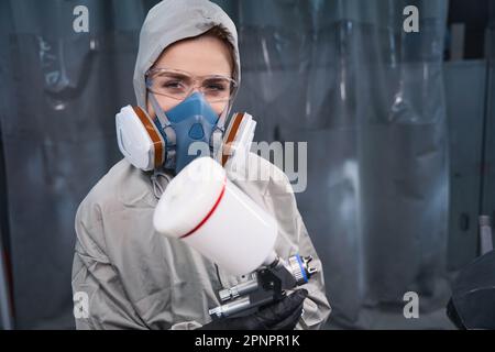 Femme attentive travaillant dans un respirateur tenant un pistolet à l'intérieur Banque D'Images