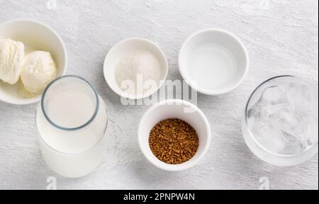 Ingrédients pour le café de Dalgona. Café instantané, lait, crème glacée, eau, glace et sucre. Arrière-plan texturé gris clair, vue du dessus Banque D'Images