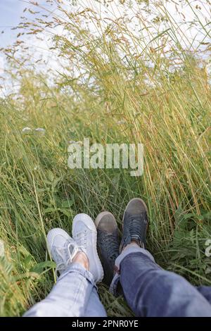 Gros plan des jambes d'une jeune femme et d'un homme couché dans un champ en été, Biélorussie Banque D'Images