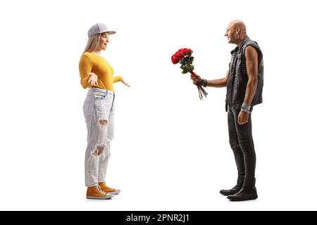 Photo pleine longueur d'un punk donnant un bouquet de roses rouges à une jeune femelle isolée sur fond blanc Banque D'Images