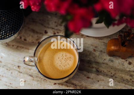 Vue en hauteur d'une tasse de café blanc sur une table à côté d'une plante à fleurs Banque D'Images