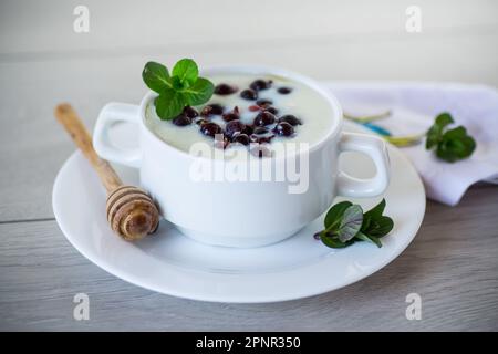 Porridge de semoule de lait cuit avec baies et miel dans une assiette, sur une table en bois. Banque D'Images