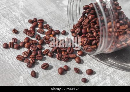 les grains de café en bouteille tombent sur la table Banque D'Images