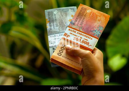 Un enfant asiatique tient l'argent indonésien dans un foyer peu profond. Concept d'épargne, de charité et de don Banque D'Images