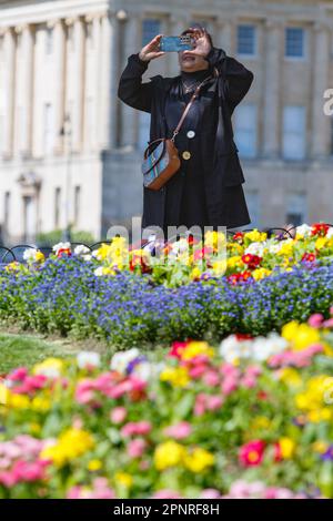 Bath, Royaume-Uni. 20th avril 2023. Avec le célèbre Royal Crescent de Bath en arrière-plan, une femme est photographiée en prenant une photo des lits de fleurs colouful du Royal Victoria Park. Les prévisionnistes prédisent que le temps sera plus frais et plus couvert dans les prochains jours. Credit: Lynchpics/Alamy Live News Banque D'Images
