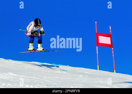 athlète féminine de skieur sur piste de ski alpin, piste enneigée sur fond bleu ciel, jeux de sports d'hiver Banque D'Images