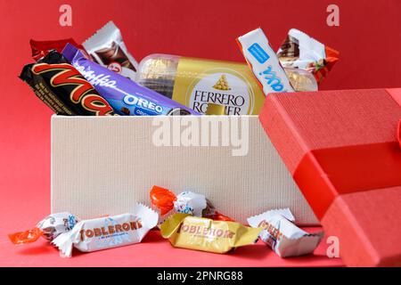 Arahal. Séville. Espagne. 18 mars 2023. Une boîte de chocolats et de bonbons de différentes marques, sur fond rouge. Le cadeau idéal pour ceux qui ont de l'humour Banque D'Images