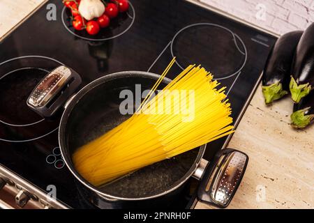 une hôtesse féminine dans la cuisine prépare de délicieux spaghetti Banque D'Images