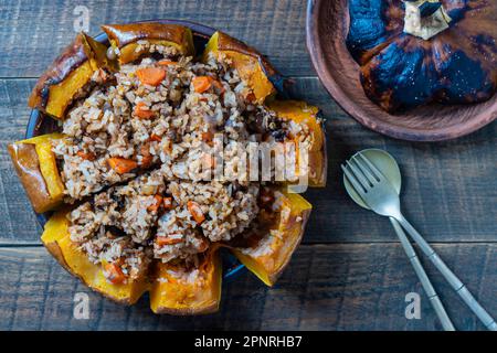 Grande citrouille cuite avec un gros plan de remplissage. Citrouille d'orange farcie, cuite au four, remplie d'un savoureux mélange de riz, de raisins secs et d'épices sur W Banque D'Images