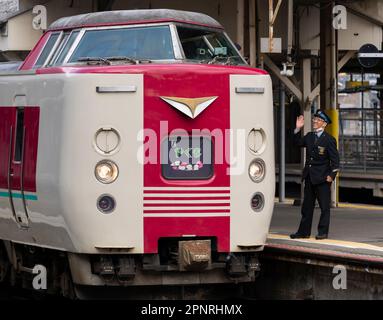 Un membre de l'équipage de JR West se rend par vagues à un train express Yakumo de la série 381 au départ à la gare Yonago dans la préfecture de Tottori, au Japon. Banque D'Images