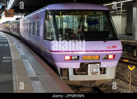 Un train express JR West 381 Series Super Yakumo aux couleurs violettes spéciales à la gare d'Okayama au Japon. Banque D'Images