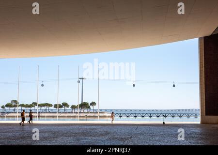 Lissabon, Portugal. 06th avril 2023. Les voyageurs d'une journée se promènent dans le 'Pavilhao de Portugal' avec son plafond en béton suspendu dans le Parc des Nations, tandis que la télécabine sur le Tage peut être vue en arrière-plan. Le 'Pavilhao de Portugal' a été construit comme un bâtiment d'exposition pour l'exposition universelle 98 pour le pays hôte Portugal selon les plans de l'architecte Siza Vieira. Crédit : Viola Lopes/dpa/Alamy Live News Banque D'Images