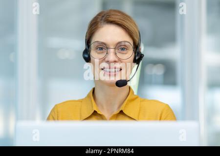 Portrait d'une femme mature au service clientèle, d'une femme d'affaires mature avec micro-casque d'appel vidéo souriant et regardant la caméra, service client en ligne du centre d'appels, bureau à l'intérieur du lieu de travail. Banque D'Images