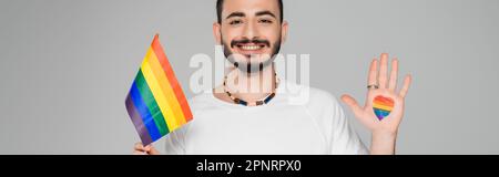 Homme homosexuel gai avec le drapeau lgbt et le coeur sur la main isolé sur gris, bannière, image de stock Banque D'Images