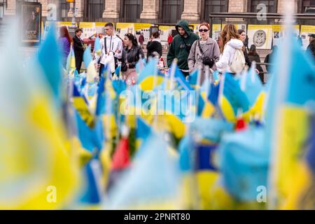 Les gens s'arrêtent devant des drapeaux ukrainiens bleus et jaunes portant les noms des soldats tombés sur Maidan Nezalezhnosti (place de l'indépendance) dans le centre de Kiev, la capitale de l'Ukraine. Les familles et les amis des militaires tués laissent des drapeaux pour leurs proches, tandis que l'invasion à grande échelle de l'Ukraine par les forces russes se poursuit. Banque D'Images