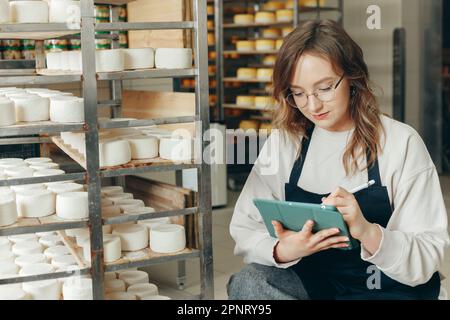 Jeune ferme femelle contrôle le processus de maturation des têtes de fromage de chèvre Banque D'Images