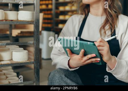 Jeune ferme femelle contrôle le processus de maturation des têtes de fromage de chèvre Banque D'Images