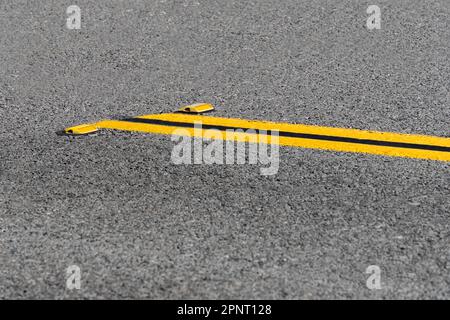 Lignes jaunes doubles sur route asphaltée avec réflecteurs Banque D'Images