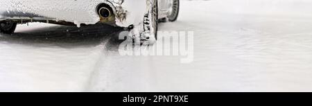 Voiture argentée recouverte de glace garée sur une route enneigée, vue détaillée de l'échappement par l'arrière-plan, arbres flous arrière-plan vide pour le texte du côté droit Banque D'Images