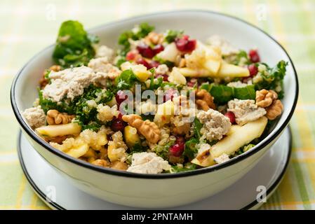 Salade kale au quinoa, pommes, noix et grenades et feta vegan maison. Banque D'Images