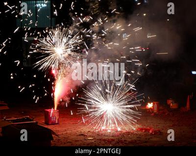 Vue aérienne d'un spectaculaire feu d'artifice extérieur, avec des éclats pyrotechniques colorés illuminant le ciel nocturne au-dessus d'un terrain sablonneux Banque D'Images