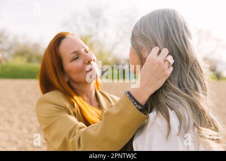 Une fille adulte caresse les cheveux d'une mère âgée aux cheveux gris. La notion de soins à une mère âgée et les relations intergénérationnelles Banque D'Images