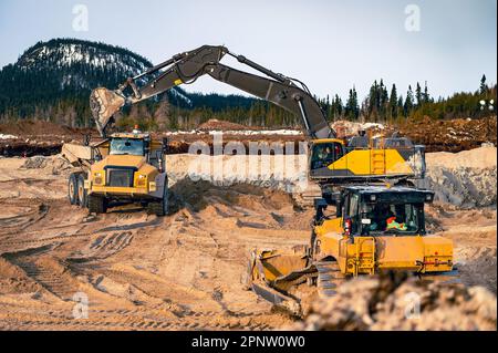 Pelle hydraulique chargeant un tombereau à benne basculante avec un sol en surface et un bulldozer en approche Banque D'Images